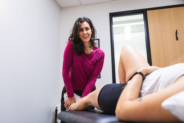 Amy Benton working as a physical therapist on the lower body of a PT client