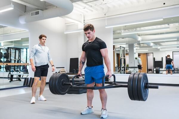 Zach LaBianco assists weightlifter with form in workout training session